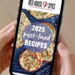 Hands holding a mobile showing the webpage of Red House Spice.
