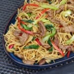 a plate of beef chow mein with sha cha sauce.