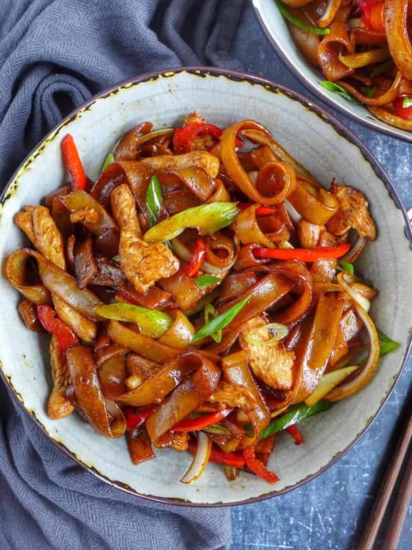 a bowl of chicken chow fun with chili oil on the side.