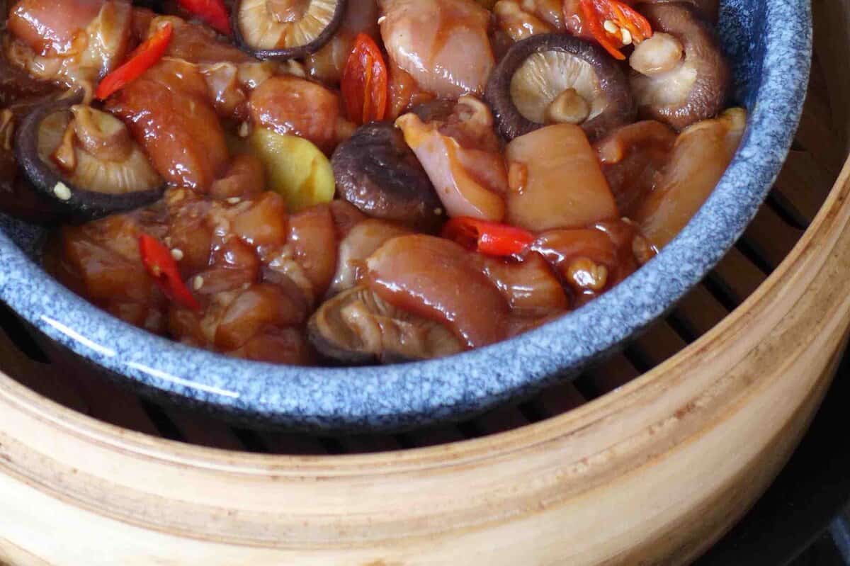 a plate of chicken in a bamboo steamer.