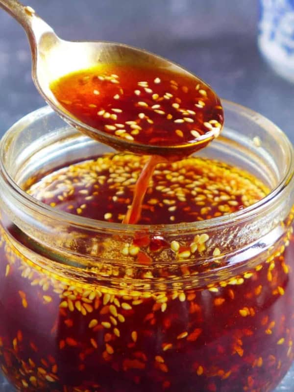Chili oil in a spoon over a jar.