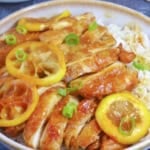 Sliced chicken and lemon over a bowl of rice.