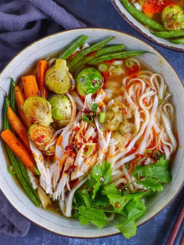 A bowl of noodle soup with turkey and vegetables