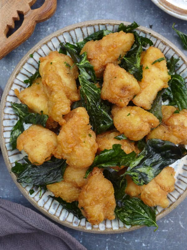 a plate of Taiwanese popcorn chicken with fried basil leaves.