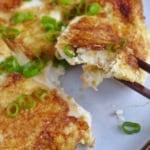 chopsticks picking up a piece of tofu omelet.