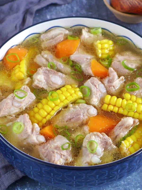 a big bowl of pork rib soup with corn and carrot.