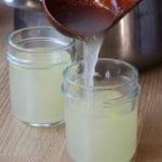 pouring chicken stock into a jar.