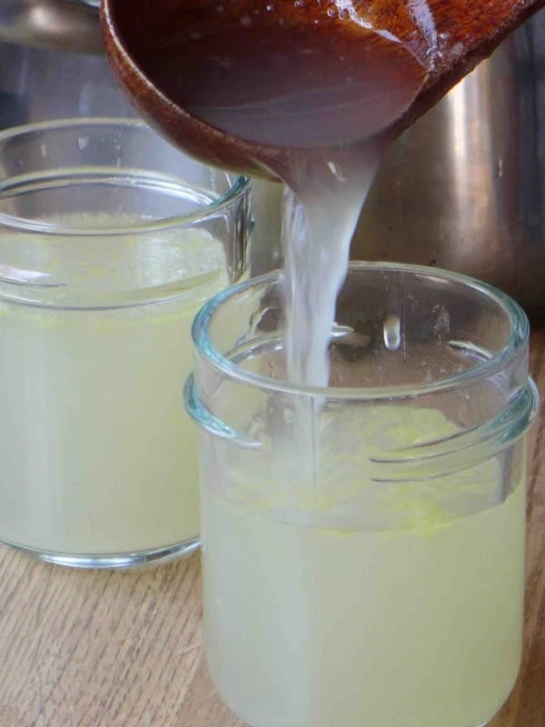 pouring chicken stock into a jar.