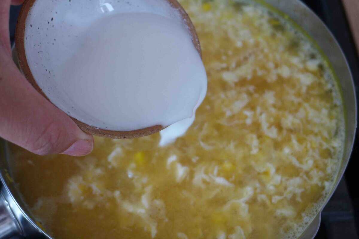 pouring cornstarch slurry into soup.