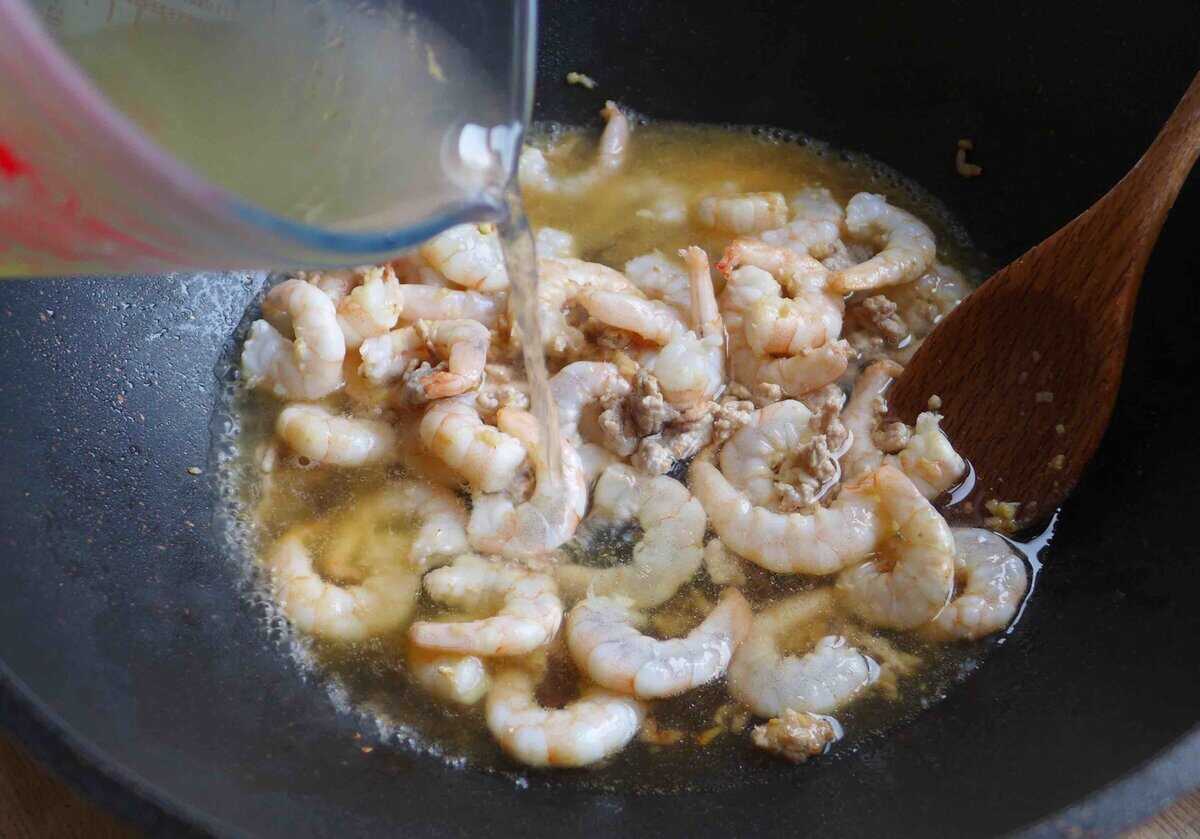 adding broth to shrimp.