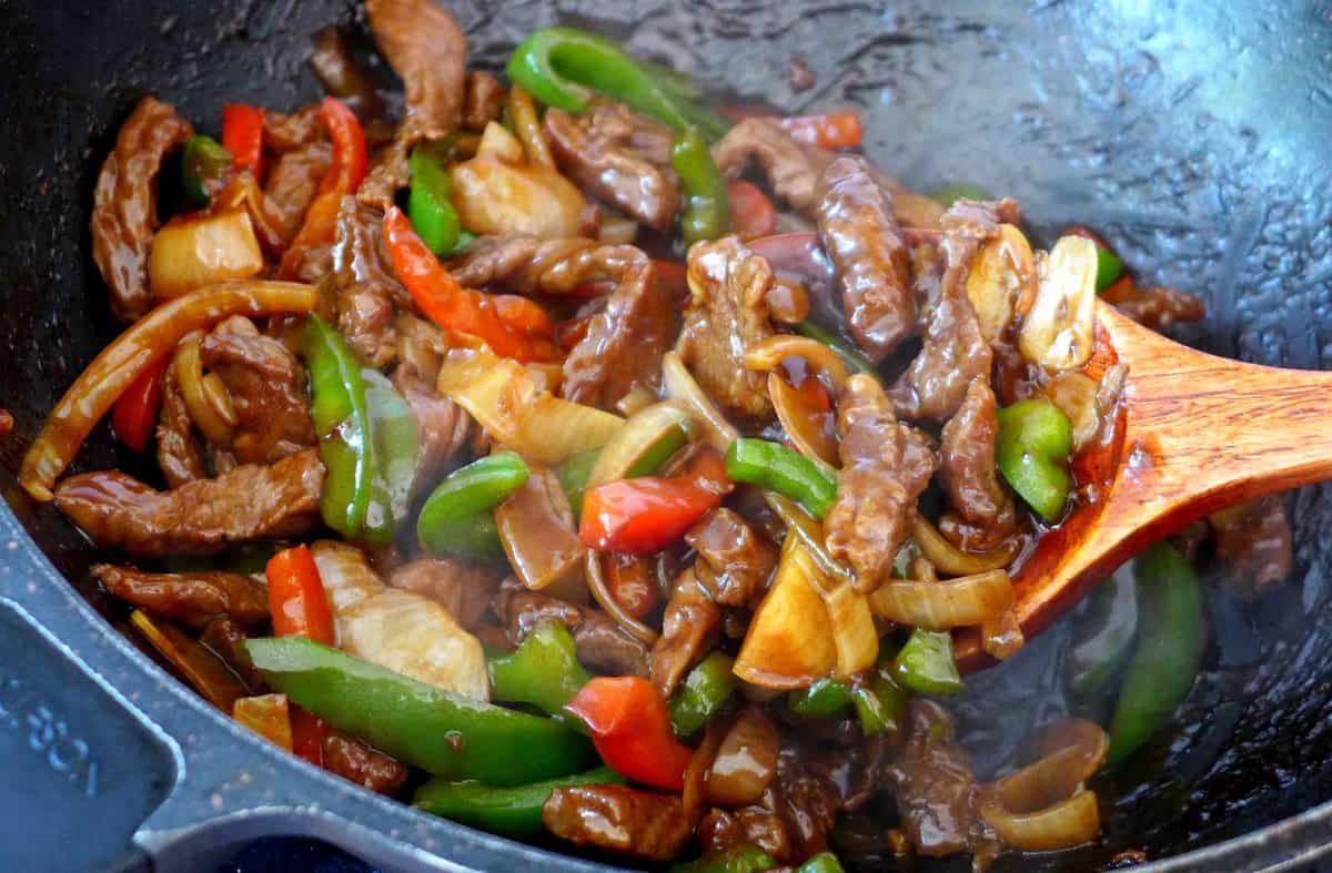 Stir-frying pepper steak in a wok.