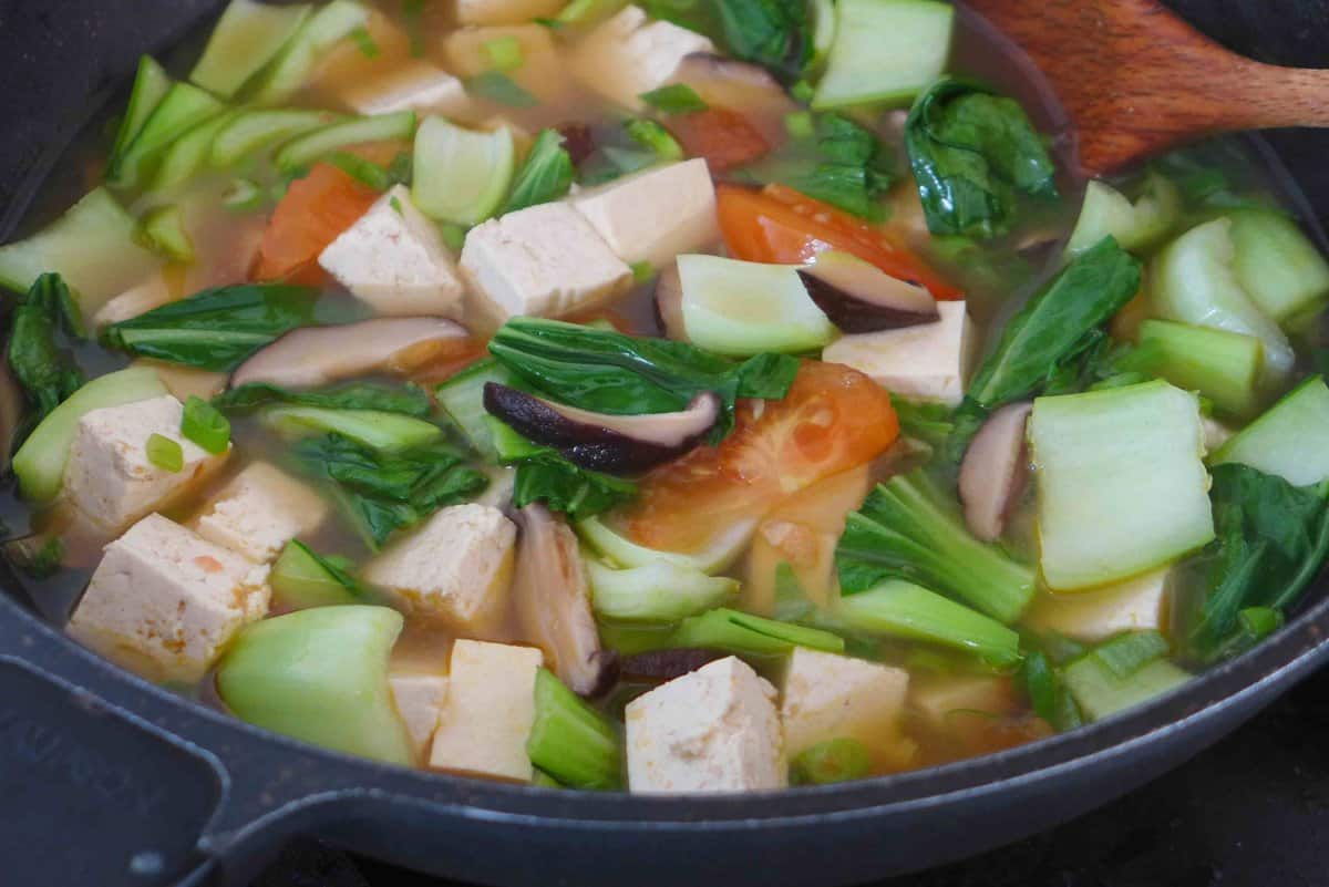 tofu and vegetable soup cooked in a wok.