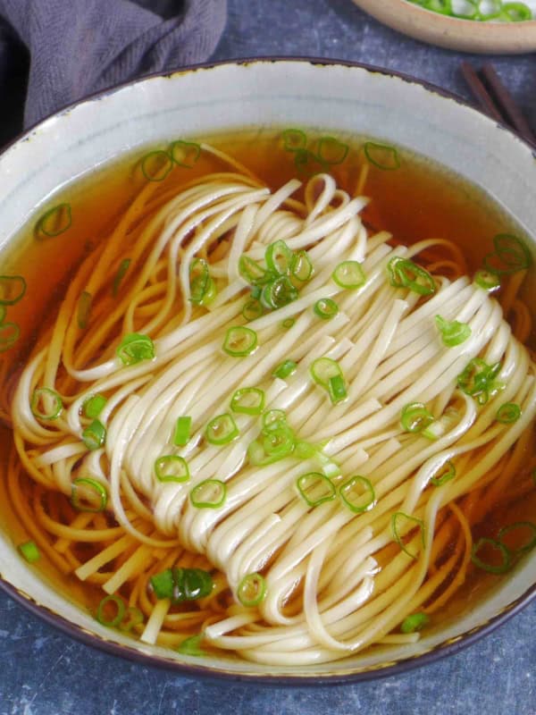 A bowl of Yang Chun Mian, noodle soup with clear broth and scallion garnish.